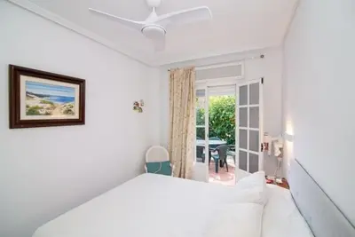 a white bedroom with a bed and a window at Pipoca's Beach in Novo Sancti Petri