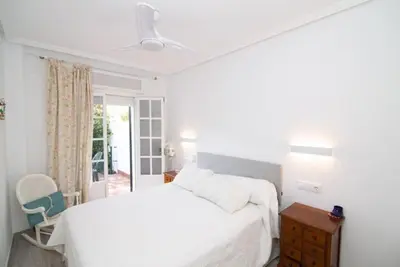 a white bedroom with a bed and a window at Pipoca's Beach in Novo Sancti Petri