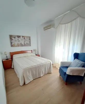 a bedroom with a bed and a blue chair at Apto 5 personas con todo equipado in San Fernando