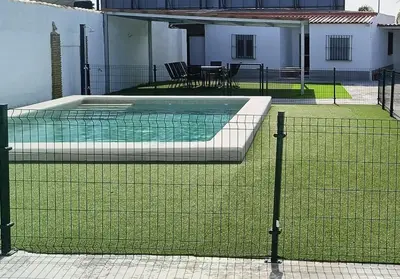 a swimming pool with green grass on a house at La Finquita in Chiclana de la Frontera