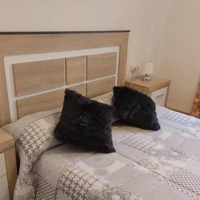 a bed with two black pillows on top of it at Apartamento ESPERANZA DE LA YEDRA in Jerez de la Frontera