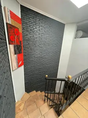 a staircase with a black brick wall with a painting at Magnifico Bungalow 2 plantas 110 m,con 3 piscinas in San Fernando