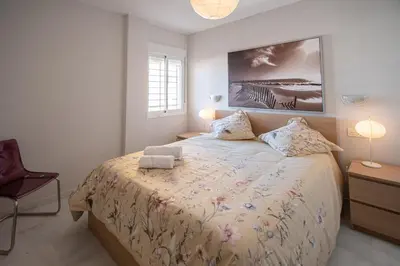 a bedroom with a large bed and a chair at Apartamentos El Ático de Hércules in Cádiz