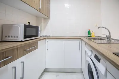 a kitchen with a microwave and a sink at Apartamentos El Ático de Hércules in Cádiz