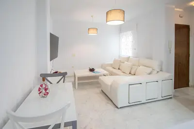 a white living room with a white couch and a table at Apartamentos El Ático de Hércules in Cádiz