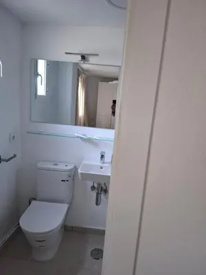 a white bathroom with a toilet and a sink at Ugaldenea- Playa in Chiclana de la Frontera