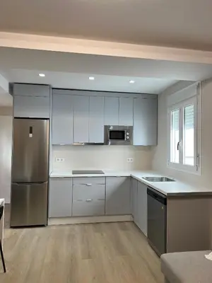 a kitchen with white cabinets and a stainless steel refrigerator at Piso del centro in Sanlúcar de Barrameda
