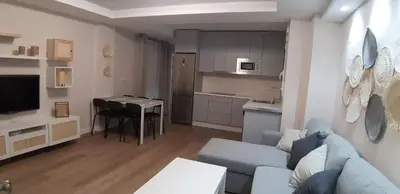 a living room with a blue couch and a kitchen at Piso del centro in Sanlúcar de Barrameda
