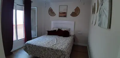 a bedroom with a bed with pillows and a window at Piso del centro in Sanlúcar de Barrameda