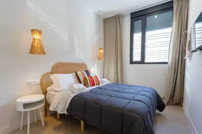 a bedroom with a bed with a blue blanket and a window at BAHIA Suites by Cadiz4Rentals in Cádiz