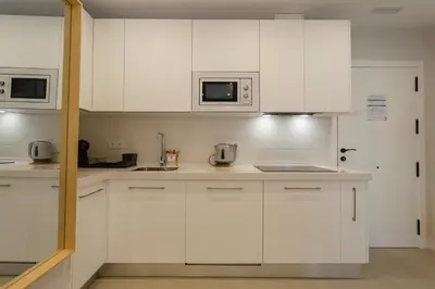 a white kitchen with white cabinets and appliances at BAHIA Suites by Cadiz4Rentals in Cádiz