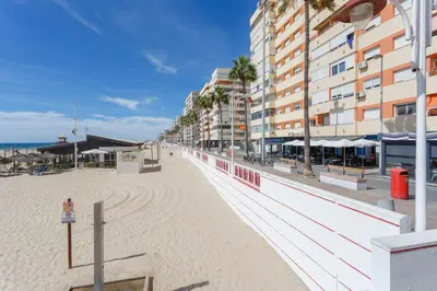 a sandy beach with a building and the ocean at BAHIA Suites by Cadiz4Rentals in Cádiz