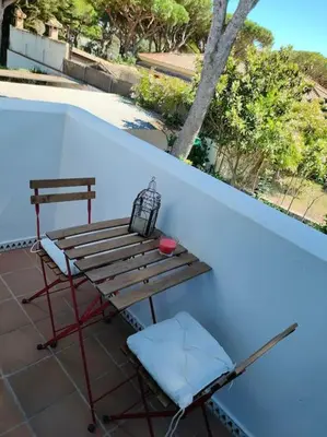 a bench and a table and a chair on a balcony at La Barrosa, una playa inigualable in Novo Sancti Petri