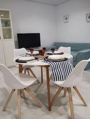 a dining room table with white chairs and a laptop at La Barrosa, una playa inigualable in Novo Sancti Petri