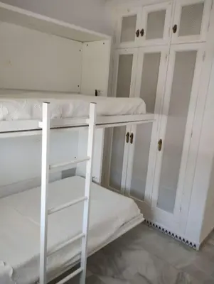 a room with white bunk beds and a mirror at La Barrosa, una playa inigualable in Novo Sancti Petri