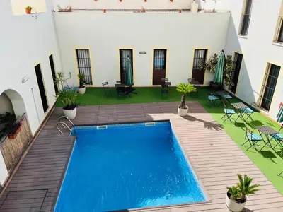 a swimming pool in the middle of a courtyard with a house at patio de luja centro parking y piscina in El Puerto de Santa María
