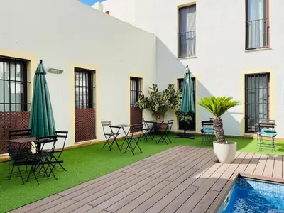 a patio with chairs and umbrellas and a pool at patio de luja centro parking y piscina in El Puerto de Santa María