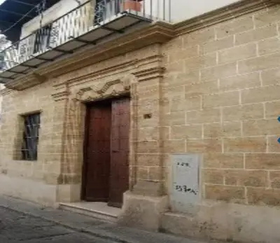 a brick building with a door and a balcony at patio de luja centro parking y piscina in El Puerto de Santa María