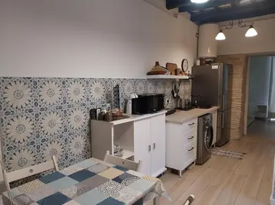 a kitchen with a table and a refrigerator and a stove at Casatuya in Jerez de la Frontera