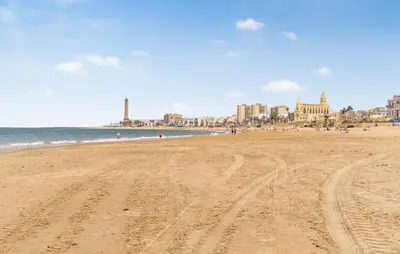 a beach with tracks in the sand and the ocean at 2 Bedroom Amazing Apartment In Chipiona in Chipiona