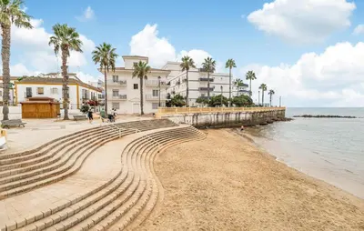 a beach with palm trees and buildings and the ocean at 2 Bedroom Amazing Apartment In Chipiona in Chipiona