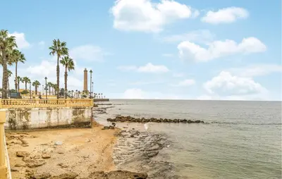 a view of a beach with palm trees and the ocean at 2 Bedroom Amazing Apartment In Chipiona in Chipiona