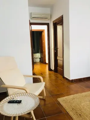 a living room with a white chair and a table at Una casa en el lago in Arcos de la Frontera