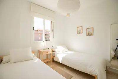 two beds in a white room with a window at Preciosa casa a 100 m de Bajo de Guía en Sanlúcar in Sanlúcar de Barrameda