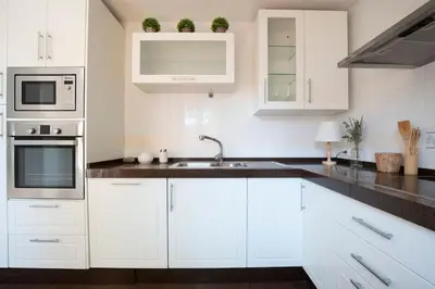 a white kitchen with white cabinets and a sink at Preciosa casa a 100 m de Bajo de Guía en Sanlúcar in Sanlúcar de Barrameda