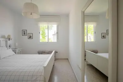 a white bedroom with a bed and a mirror at Preciosa casa a 100 m de Bajo de Guía en Sanlúcar in Sanlúcar de Barrameda