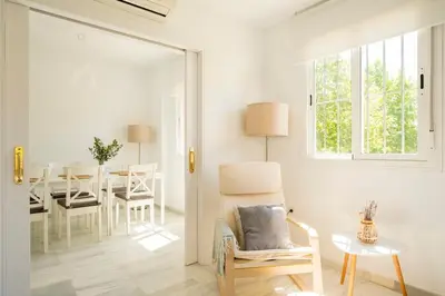 a white living room with a table and a chair at Preciosa casa a 100 m de Bajo de Guía en Sanlúcar in Sanlúcar de Barrameda
