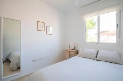 a white bedroom with a large window and a bed at Preciosa casa a 100 m de Bajo de Guía en Sanlúcar in Sanlúcar de Barrameda