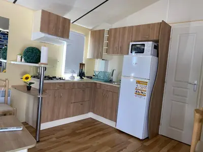 a kitchen with a white refrigerator and wooden cabinets at Casita la ilusión in Conil de la Frontera