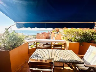 a table and chairs on a balcony with a blue umbrella at Ático horizonte in Sanlúcar de Barrameda