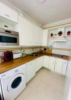 a kitchen with white cabinets and a washer and dryer at Ático horizonte in Sanlúcar de Barrameda
