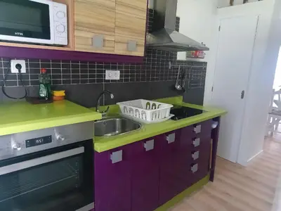 a kitchen with purple cabinets and a sink and a microwave at Villasultana 1 in Chipiona