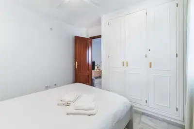 a white bedroom with a bed with two towels on it at Precioso apartamento con terraza independiente en pleno centro in El Puerto de Santa María