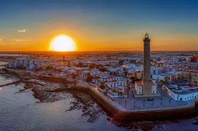 an aerial view of a city with a lighthouse at sunset at El Cerro de Villasultana, a 3min a pie de playa VUTCA21313 in Chipiona