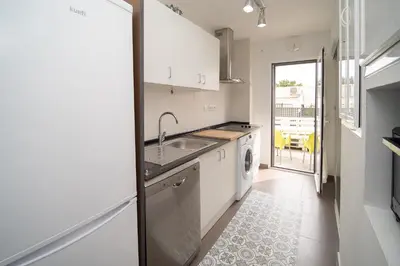 a white kitchen with a sink and a dishwasher at Cimbra 15 in Sanlúcar de Barrameda