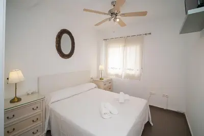a white bedroom with a bed and a ceiling fan at Cimbra 15 in Sanlúcar de Barrameda
