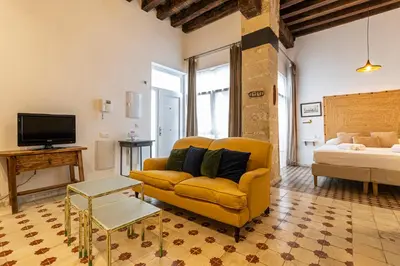 a living room with a yellow couch and a bed at Allo Apartments Amargura II Centro Loft in Jerez de la Frontera
