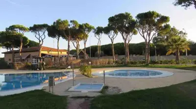 a swimming pool in a yard with trees in the background at Adosado Casa Melo Playa la Barrosa La Balconera in Poblado de Sancti Petri
