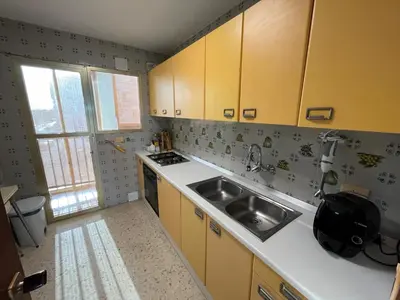 a kitchen with yellow cabinets and a sink at Apartamento Ana in El Puerto de Santa María