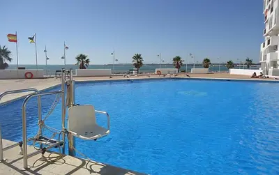 a blue swimming pool with a chair next to a building at Apartamento Ana in El Puerto de Santa María