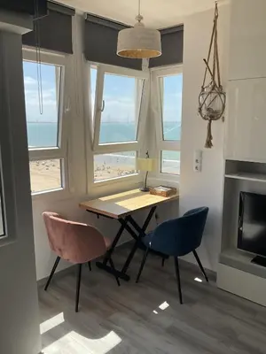 a dining room with a table and chairs with a view of the beach at Azvalia estudio Valdelagrana in El Puerto de Santa María