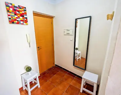 a hallway with a mirror and two white tables at Milagros Central Apartments in El Puerto de Santa María