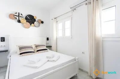 a white bedroom with a bed and a window at Torre Argantonio by LiveWork in Cádiz