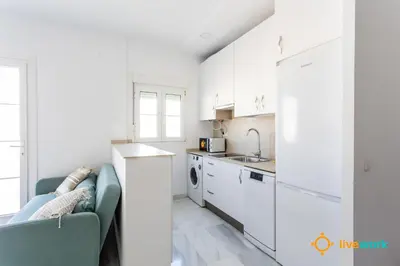 a kitchen with white cabinets and a green couch at Torre Argantonio by LiveWork in Cádiz