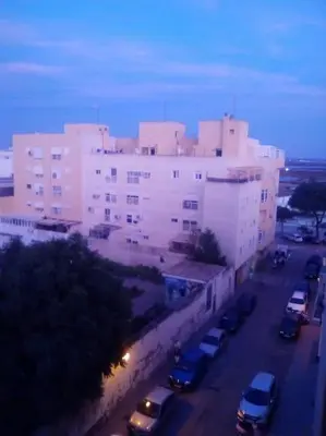 a large building with cars parked in a parking lot at Mi pisito La Maña in San Fernando