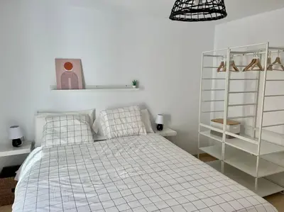 a white bedroom with a bed and a shelf at La Candela by Gades Gestión in Cádiz